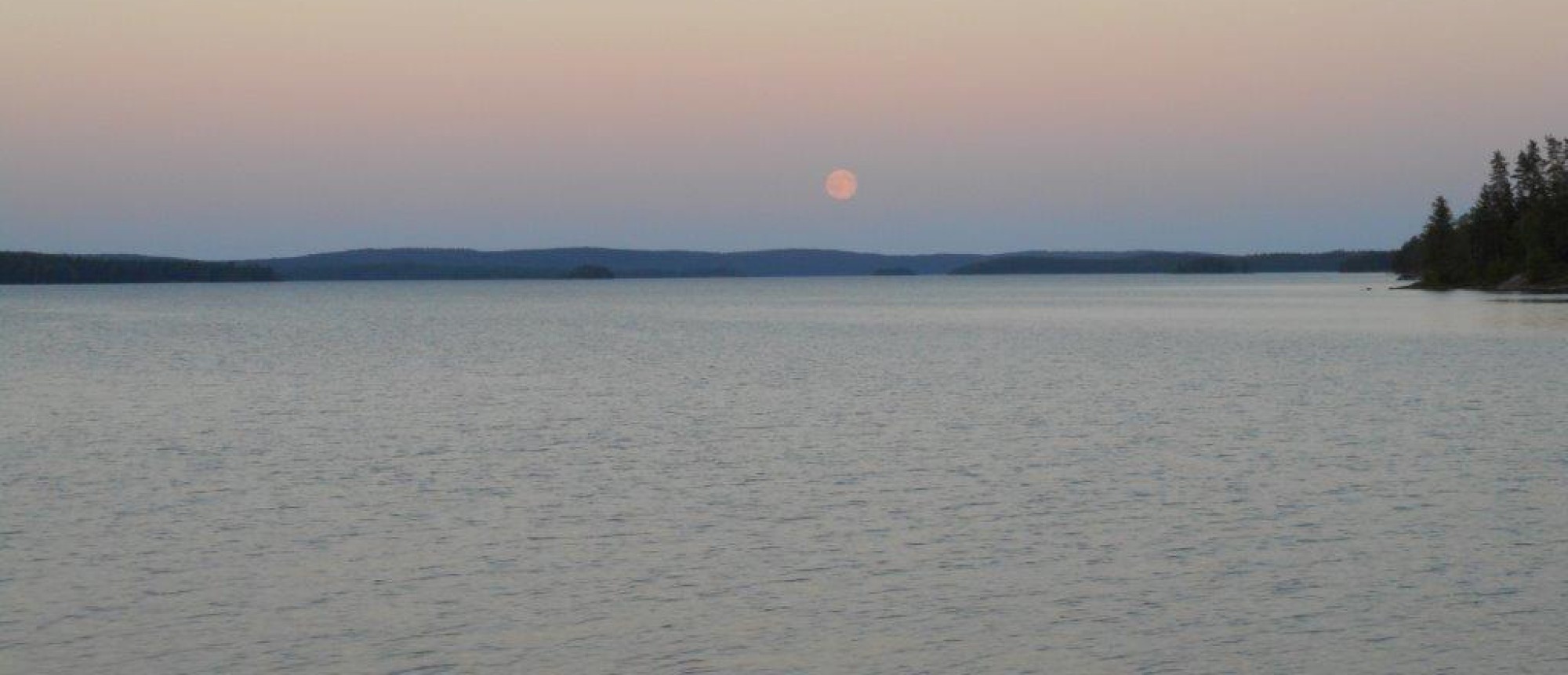 Stiller See in der Abenddämmerung mit aufgehendem Mond
